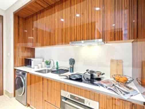 Modern kitchen with wooden cabinetry, white countertops, and stainless steel appliances.