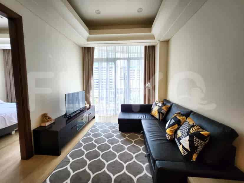 Modern living room featuring a black leather sofa, TV, and large windows.