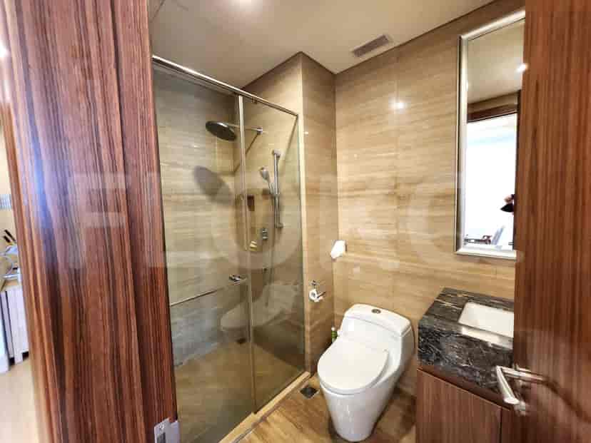Modern bathroom with a glass shower, toilet, and marble wall.