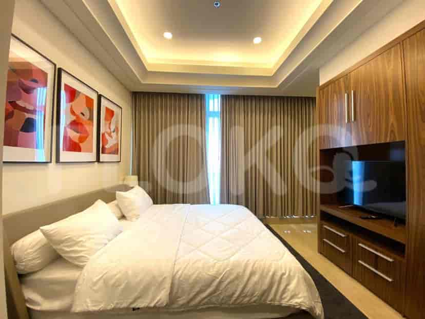 A well-lit bedroom with a large bed and a wall-mounted TV.