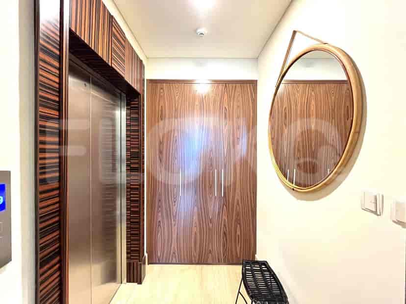 Hallway with a mirror, wooden paneling, and elevator.