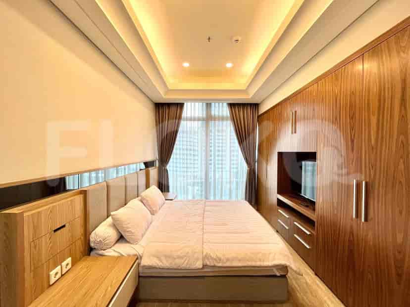 A well-lit bedroom featuring a bed and a wooden wardrobe.
