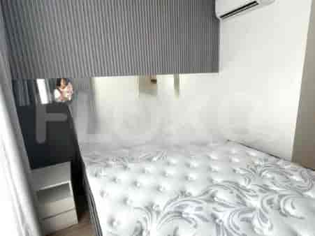 A bedroom with a bed, mirror and a side table.