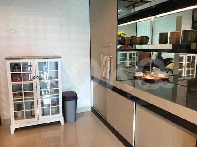 Kitchen area with cabinets, white glass shelves, and a trash can.