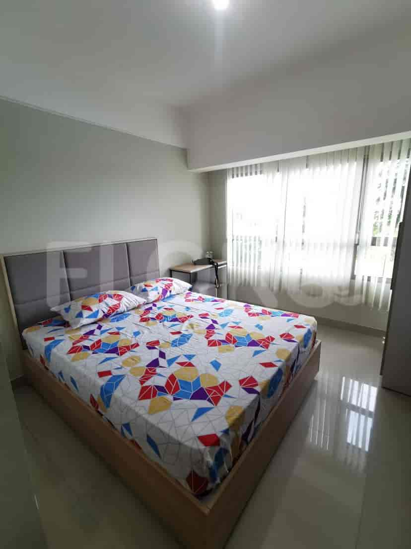 A bedroom featuring a double bed with colorful bedding and a window with blinds.
