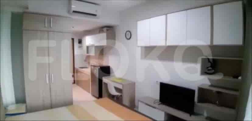 A combined bedroom and living space showing a bed, closet, and kitchen.