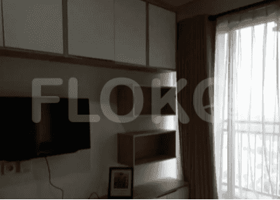 A studio apartment with a wall-mounted TV, cabinets, and access to the balcony.