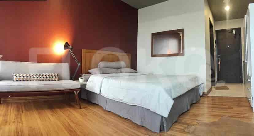 A cozy bedroom with a wooden bedframe, sofa, and a modern lamp.