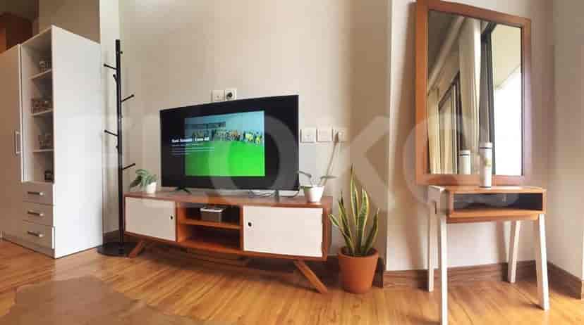 Living room with a TV console, mirror, and an adjacent open-plan bedroom.
