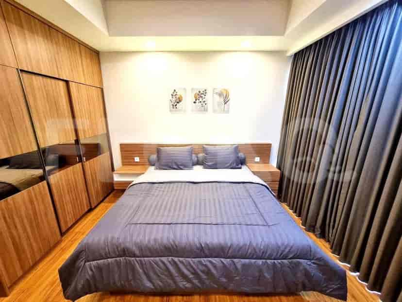 A modern bedroom with a large bed, wooden cabinets, and large window with curtains.