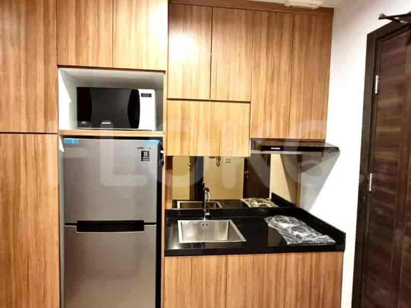 The kitchen has wooden cabinets, a refrigerator, a microwave and a sink.