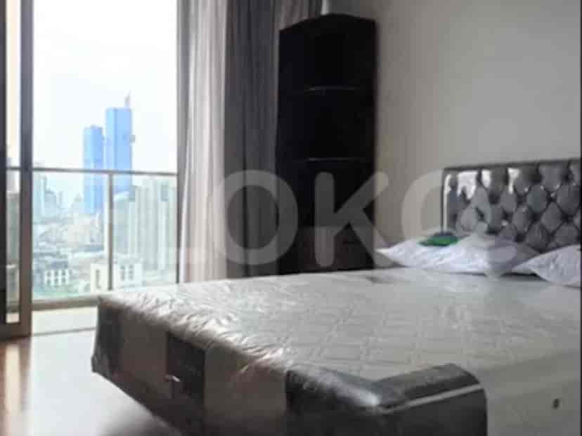 A bedroom with a large bed next to a window overlooking a cityscape.