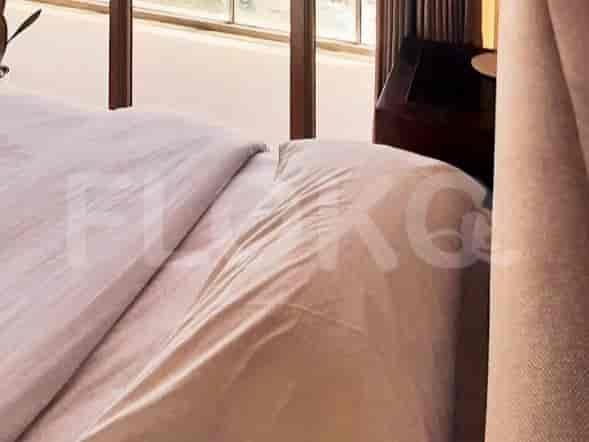 A bedroom showing a neatly made bed with a city view through the window.