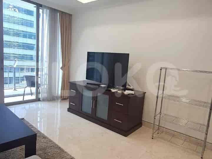 Living room with a large TV on a wooden cabinet, a balcony view, and a wire rack.