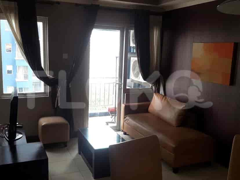 Ruang tamu dengan sofa coklat, meja kecil, dan jendela.