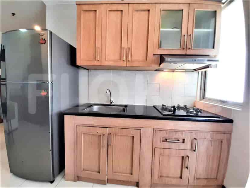 Dapur kecil dengan lemari kayu, kulkas baja tahan karat, dan kompor.