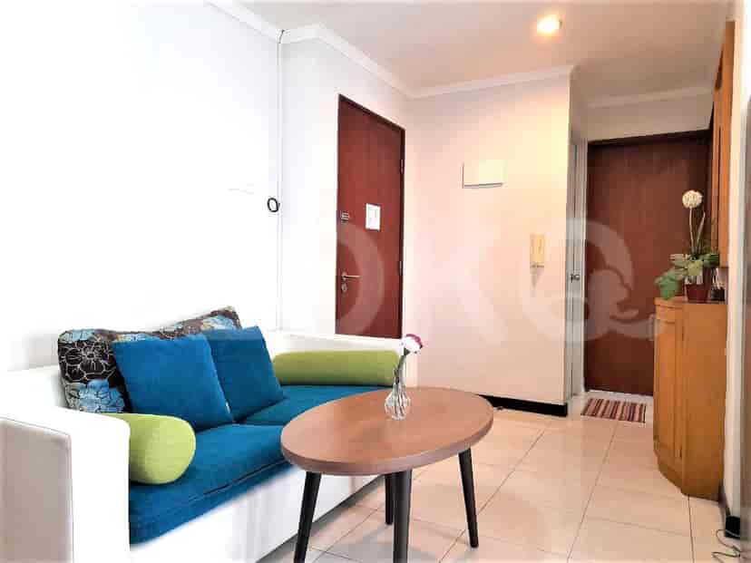 Ruang tamu dengan sofa putih, meja kopi bundar, dan pintu.
