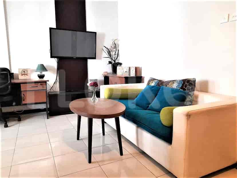 Ruang tamu dengan sofa teal, meja kopi bundar, dan TV yang dipasang.