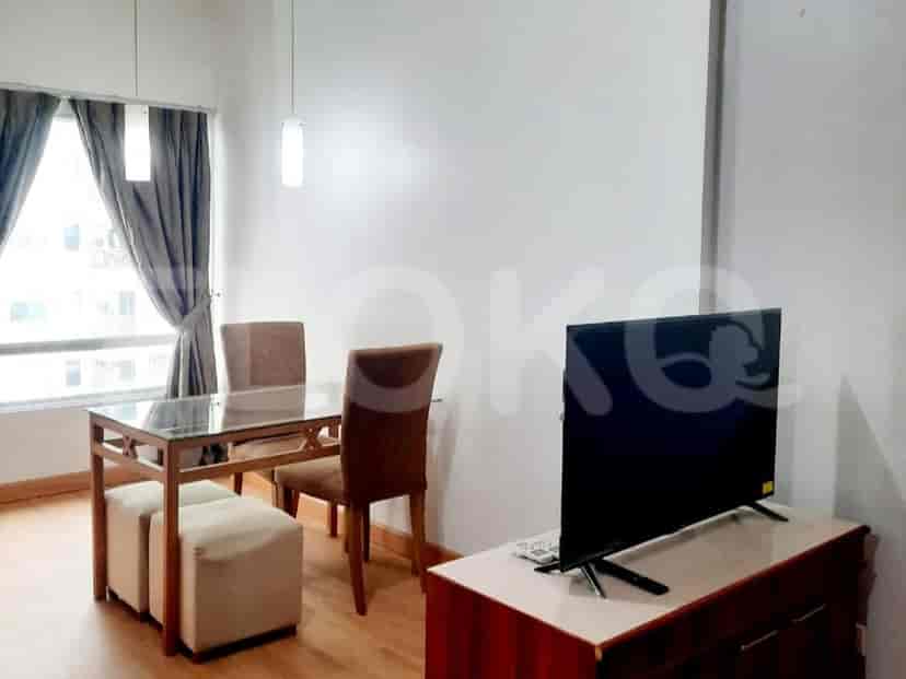 A dining area with a glass-top table and chairs, alongside a TV cabinet.
