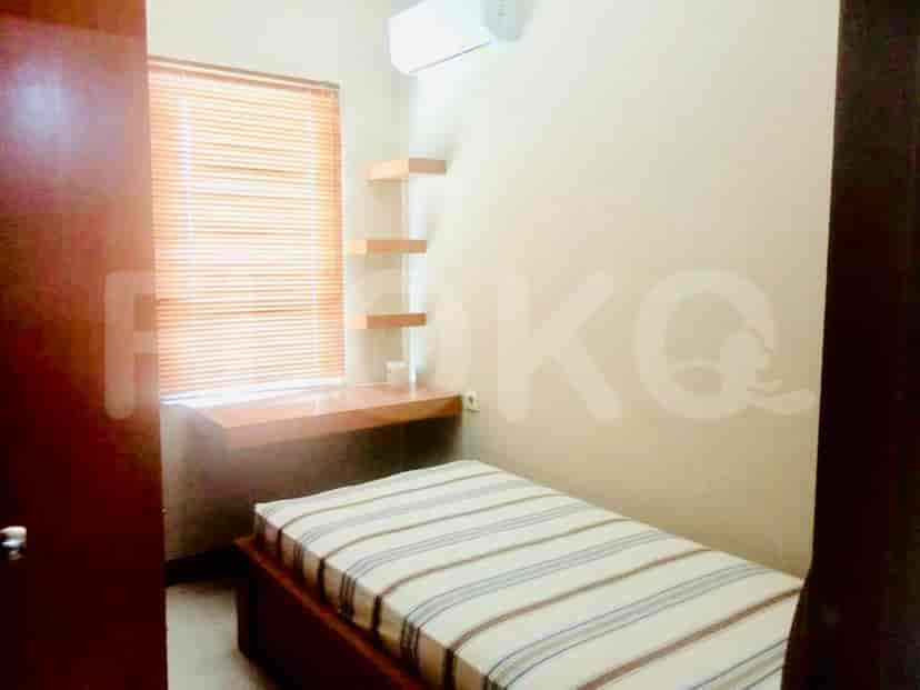 A bedroom with a single bed, shelves, and a small desk.