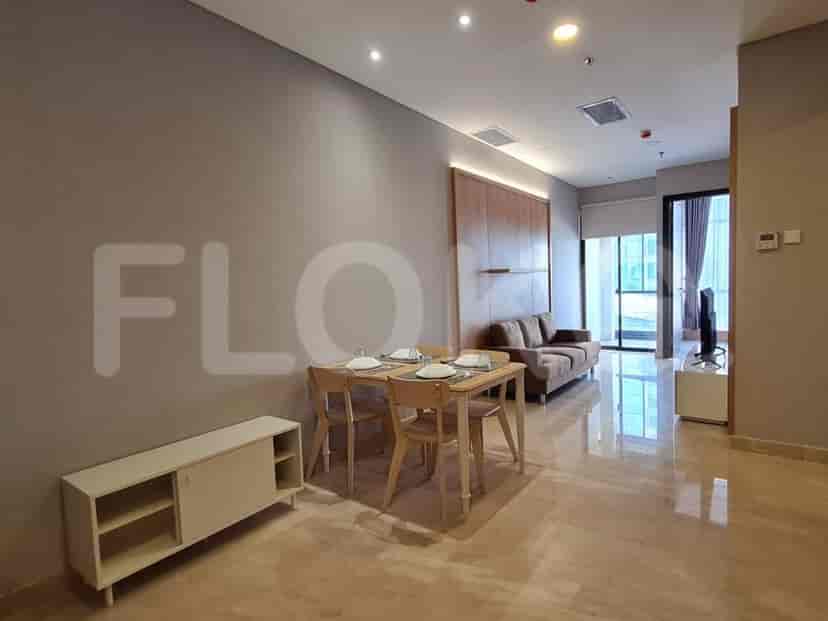 Well-lit open-plan living and dining area with a sofa, dining table, and a view of the exterior.