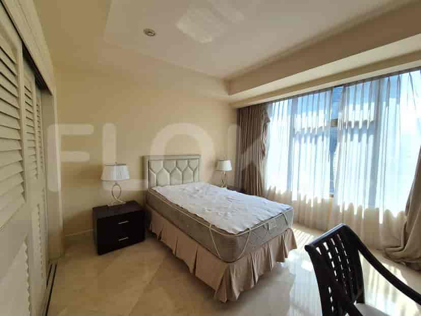 A bedroom with a bed, nightstands, and large windows.