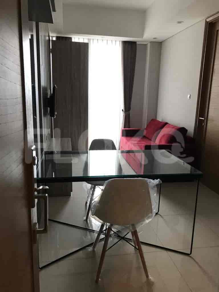 Dining area with a glass table and chairs, leading to a living area.