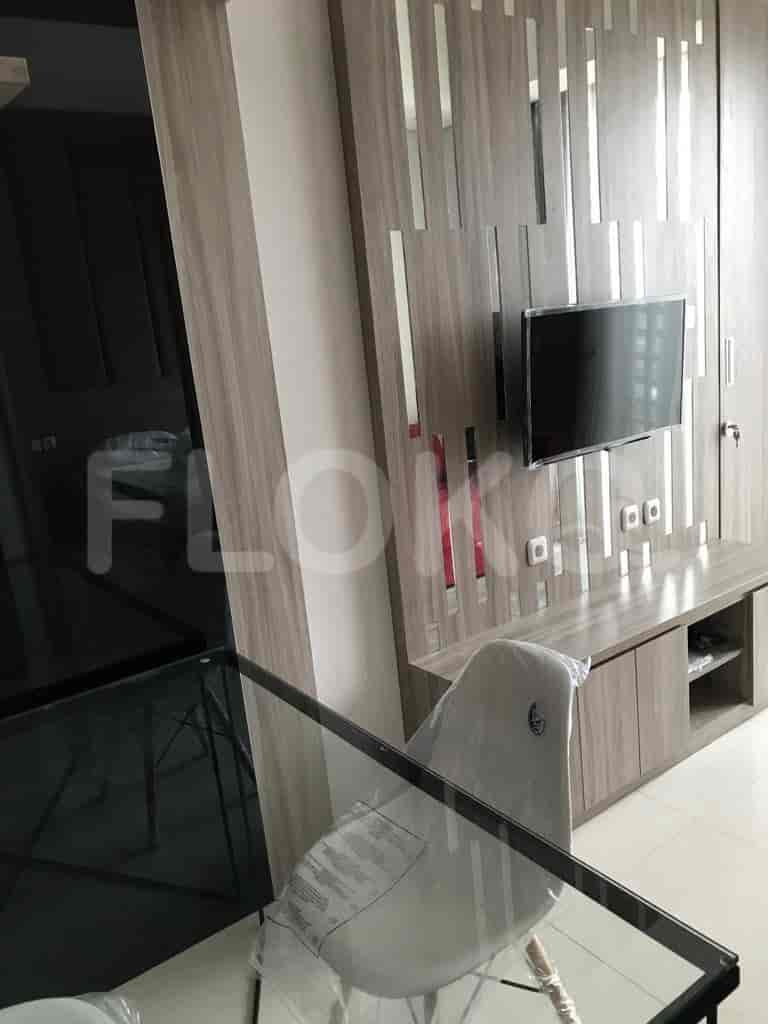 Living room with a glass dining table, TV unit, and sofa.