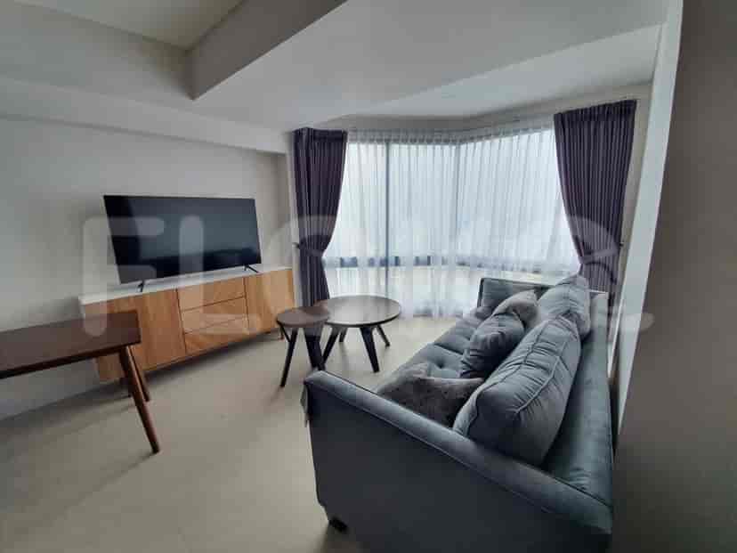 Modern living room with a grey sofa, wooden TV console, and large windows.