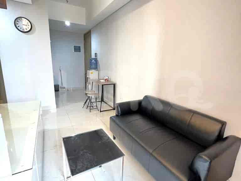 A simple living space with a sofa, table, and a small dining area.