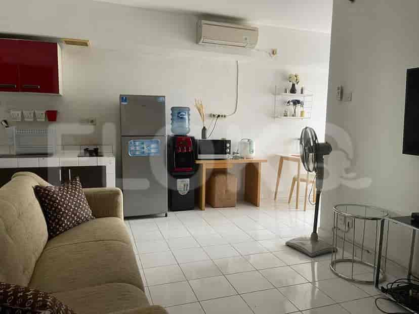 Kitchen area with a refrigerator, water dispenser, and microwave connected to the living room.