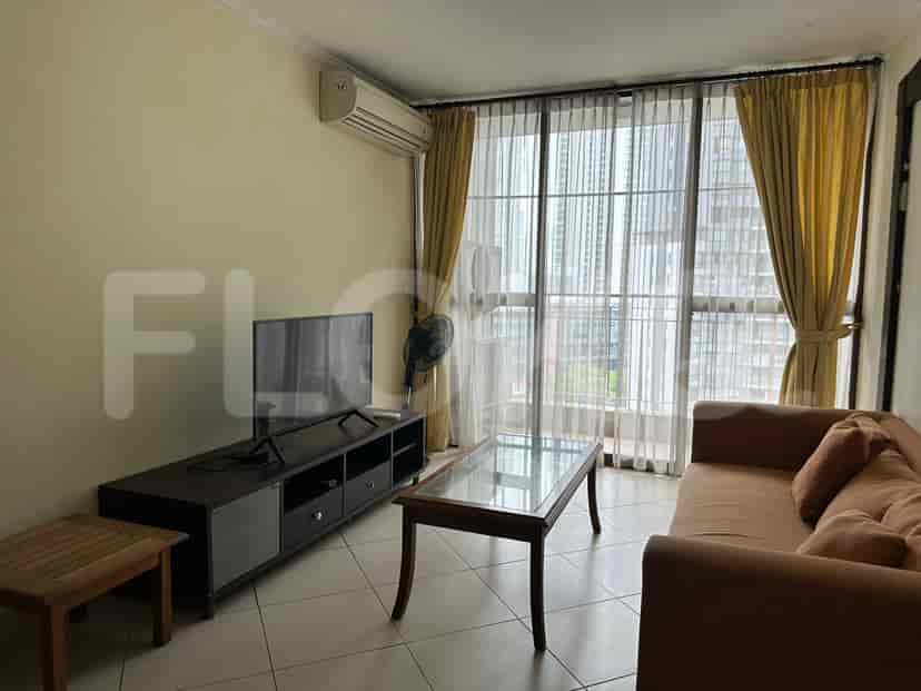 Living room with a sofa, TV, and large windows.