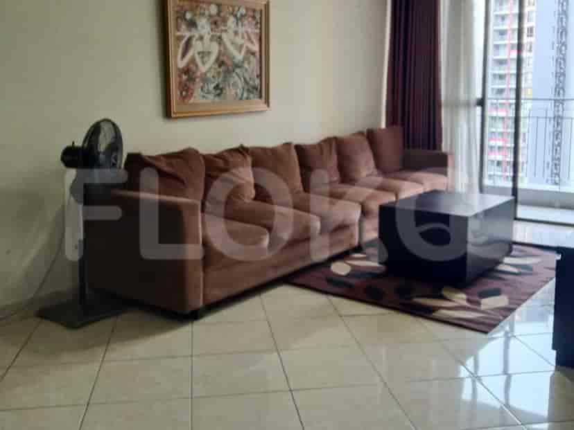 Living room featuring a brown L-shaped sofa, a black square coffee table on a patterned rug, and a fan.