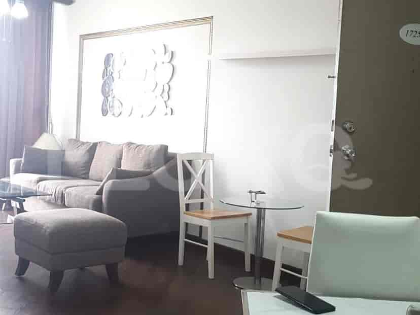 Living room with a brown sofa, ottoman, and glass table.