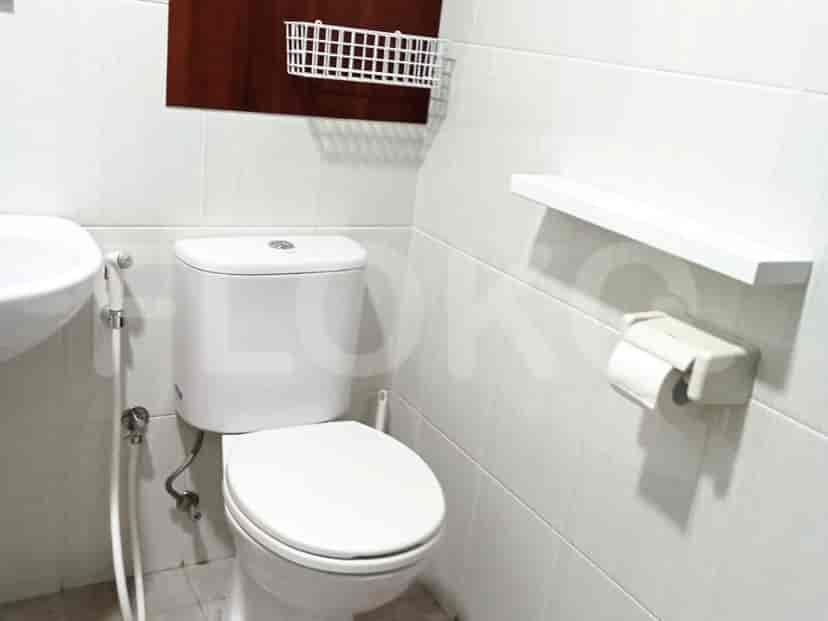 A bathroom with a toilet, sink, and white tiles.