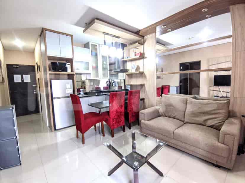 Modern apartment with kitchen, dining table, and sofa, featuring red velvet chairs.