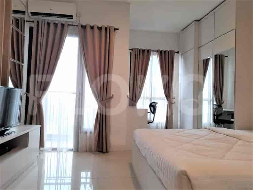A bedroom with a bed, window, and balcony access.