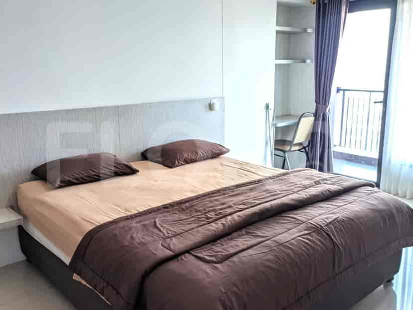 A bedroom featuring a double bed with brown bedding and a window with purple curtains.