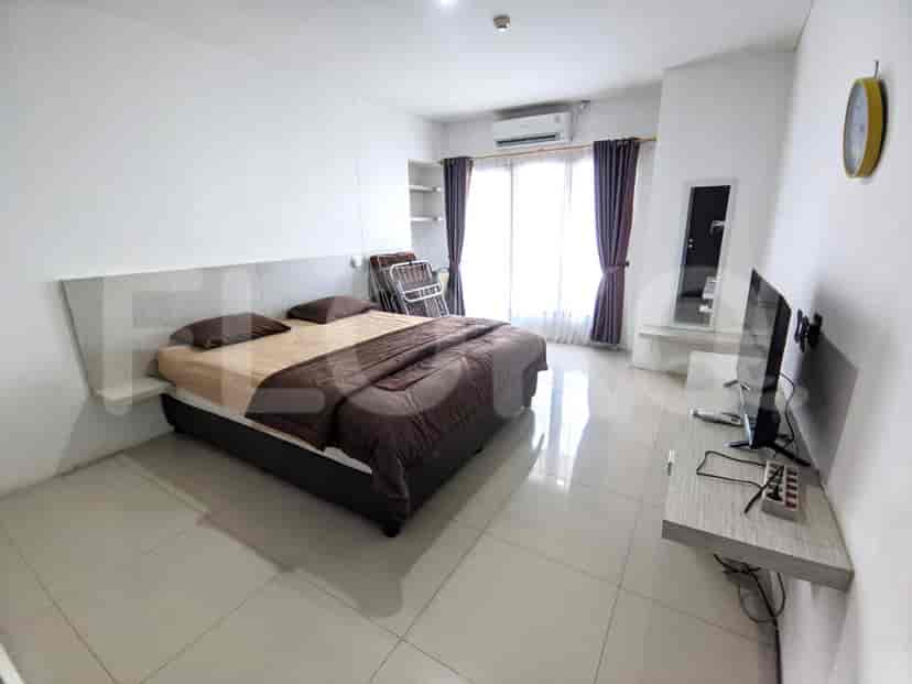 A bedroom with a double bed, TV, and a balcony.