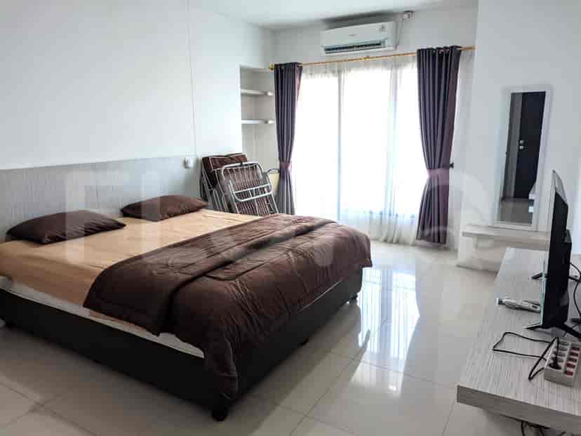 A bedroom with a double bed, TV, and a balcony.