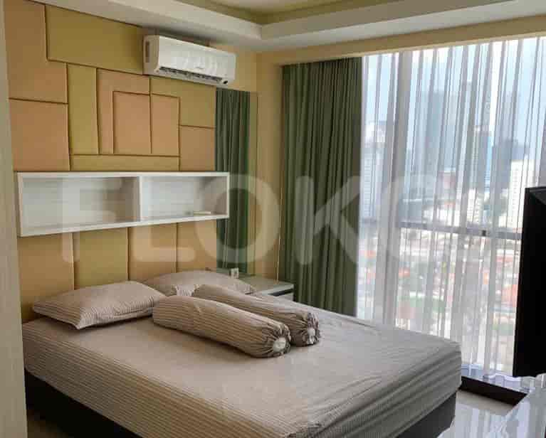 A bedroom featuring a double bed with striped bedding and a cushioned wall panel.