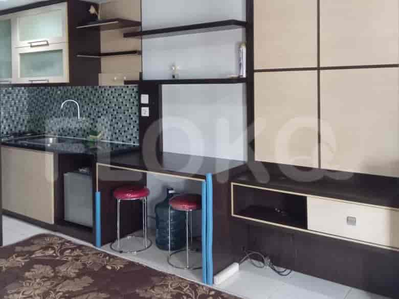 A compact kitchen with a counter, sink, and bar stools.