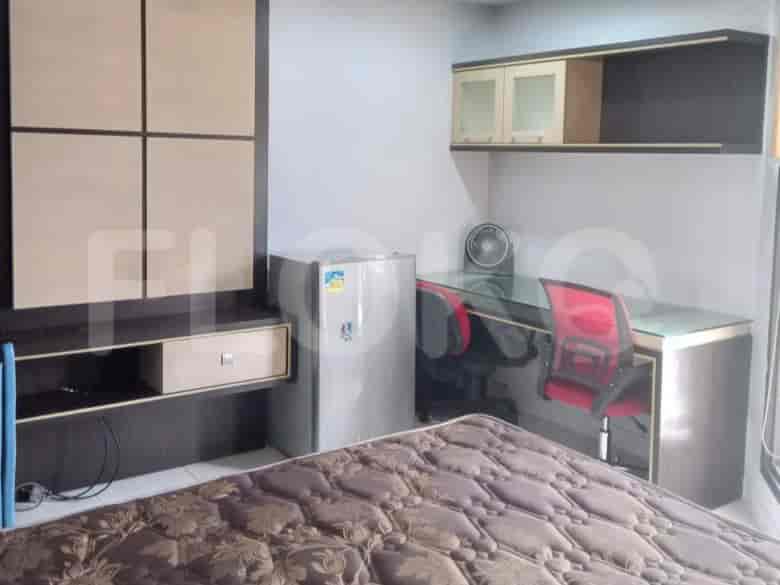 A studio apartment with a bed, desk, and refrigerator visible.