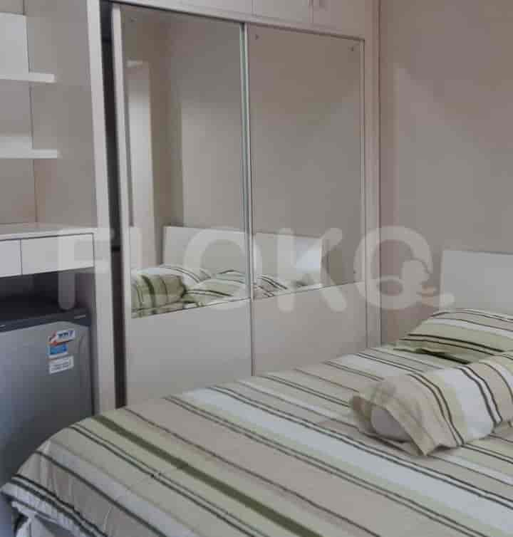 A bedroom featuring a bed, large mirror, and a refrigerator.