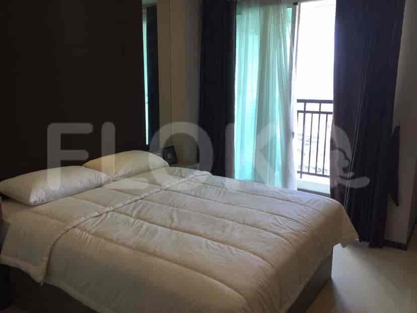 Kamar tidur dengan tempat tidur, akses balkon, dan papan kepala tempat tidur coklat tua.