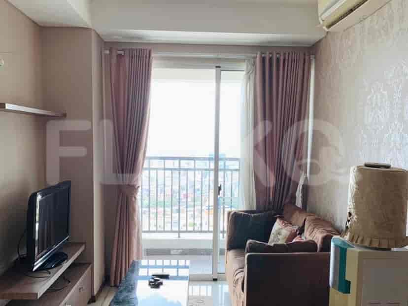 Ruang tamu dengan sofa, TV, dan akses balkon.