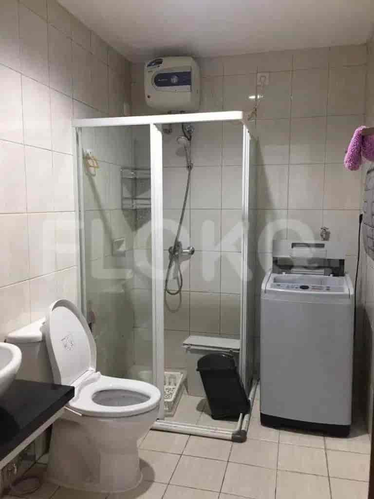 A clean bathroom with a glass shower, toilet, and washing machine.