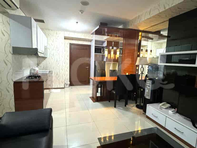 Open layout featuring a kitchen with wooden cabinets and a living area with a dining table.