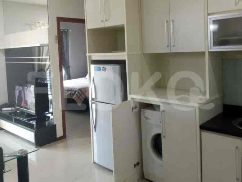 The kitchen featuring a refrigerator and washer-dryer unit, leading to the bedroom.