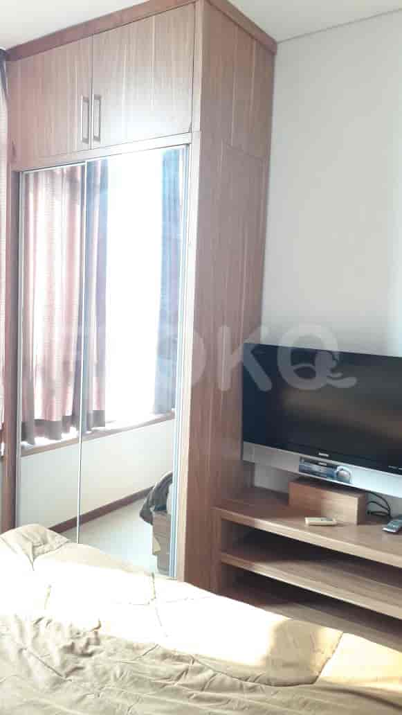 A bedroom with a TV, wardrobe, and bed.